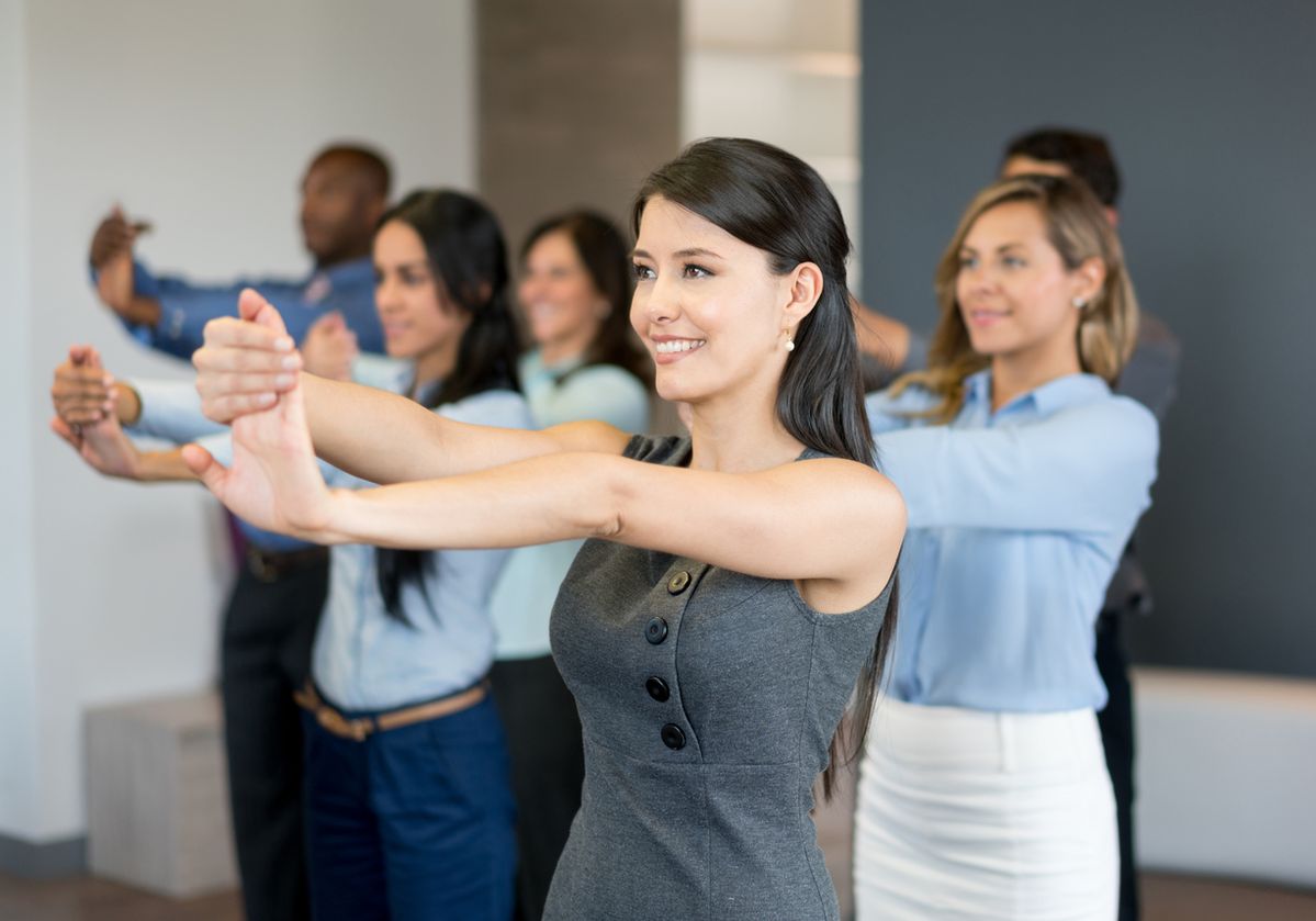 A diverse team of office workers participating in a guided stretching session, promoting active breaks and workplace wellness